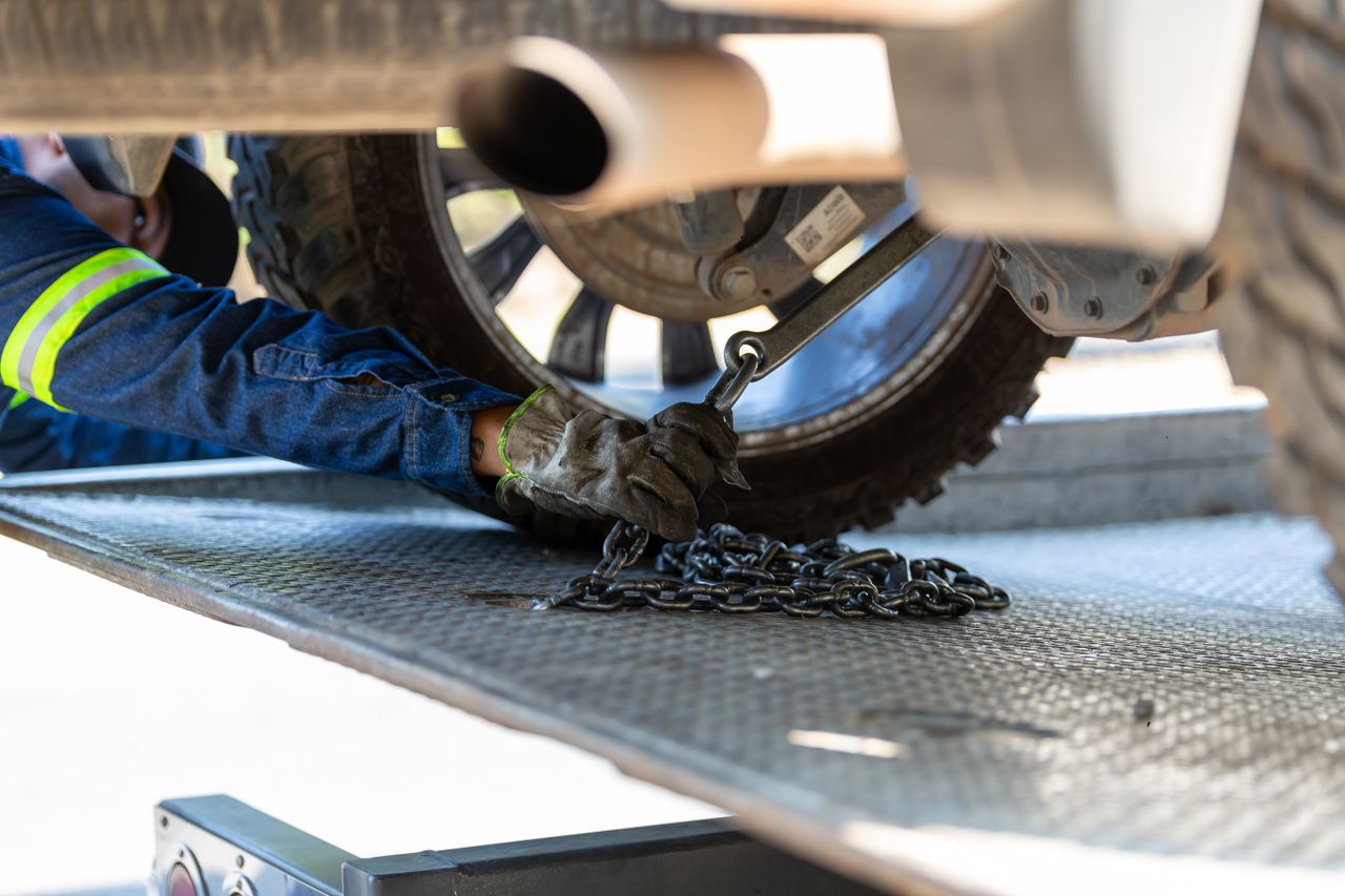 Crafting Captivating Headlines: Your awesome post title goes here Mechanic securing a vehicle on a service platform with a chain for safe towing.